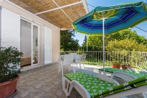 een patio met een tafel en stoelen en een parasol bij Apartments & Rooms Jokovic in Mlini