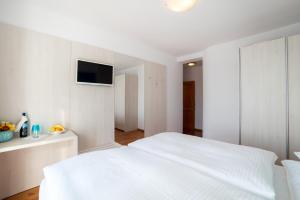 a white bedroom with a bed and a tv on the wall at Rooms Raič in Dubrovnik