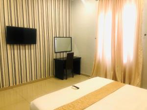 a bedroom with a bed and a tv and a window at Mayor's & Diplomat Suite in Ikeja