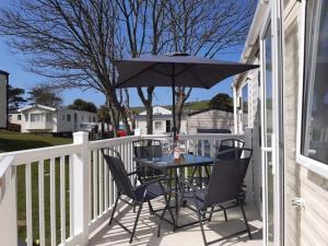 a table and chairs on a porch with an umbrella at 67 Newquay Getaway in Porth