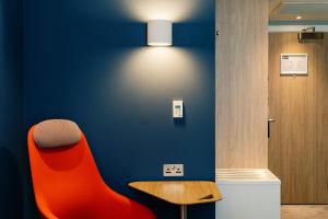 a red chair and a wooden table in a room at Holiday Inn Express Amsterdam - North Riverside by IHG in Amsterdam