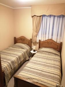 2 camas en una habitación pequeña con ventana en Departamentos amoblados - Santa Sofia., en Concepción