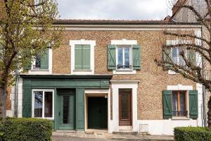 une maison en briques avec portes et fenêtres vertes dans l'établissement Les Logis de Marcoussis, à Marcoussis