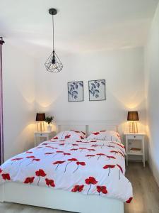 a bedroom with a white bed with red flowers on it at Holiday House Lucia in Sukošan