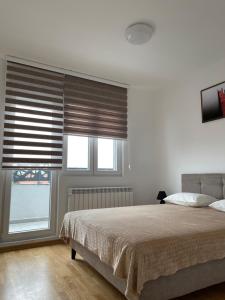 a bedroom with a bed and two windows with blinds at Royal Residence Apartmani 2 in Pančevo