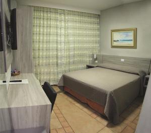 a bedroom with a bed and a table and a window at PARANÁ PALACE HOTEL in Campo Mourão