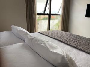 uma cama com lençóis e almofadas brancos e uma janela em 9006 Suites Natal Vista Mar em Natal