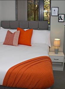 ein großes Bett mit orangefarbenen und weißen Kissen darauf in der Unterkunft Avoca Court in Birmingham