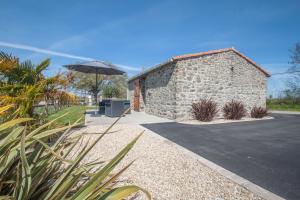 a stone building with an umbrella next to a street at Gîte du Bois Brillant in Couffé