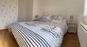 a bedroom with a bed with a white and blue blanket at L'Aéroplage, Appartement Standing Rénové Vacances 40mètres plage in Berck-sur-Mer