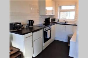 a kitchen with white cabinets and black counter tops at Exceptional Chalet near to Beach, Broads & Gt Yarmouth in Great Yarmouth