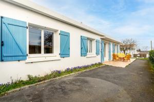 ein Haus mit blauen Rollläden und Stühlen auf einer Auffahrt in der Unterkunft Maison de vacances à Saint Hilaire de Riez in Saint-Hilaire-de-Riez