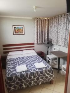 Un dormitorio con una cama y una mesa. en La Posada de Valdez, en Camaná