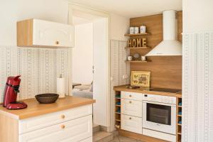 uma cozinha com armários brancos e um forno com placa de fogão em Fewo-llojan em Wiesmoor