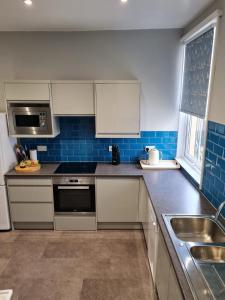 una cocina con armarios blancos y azulejos azules en Brigg View Holiday Apartment, en Filey 17 fotos más