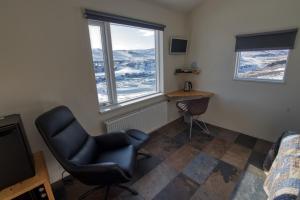 a bedroom with a chair and a desk and two windows at Fossatún Country Hotel in Fossatún