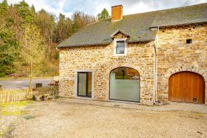 een stenen huis met een garage en een houten deur bij Le Moulin de Bosson - Ourasi in Ferrières