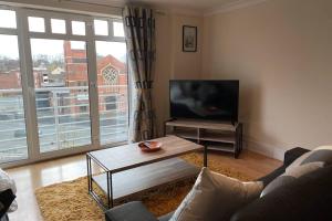 een woonkamer met een bank, een tafel en een tv bij City Central Apartment in Coventry