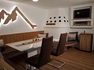 a dining room with a table and chairs and a tv at Apart ZIRMZEIT in Huben