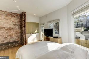 ワシントンにあるLofty DC Sanctuaryの白いベッドとレンガの壁が備わるベッドルーム1室が備わります。