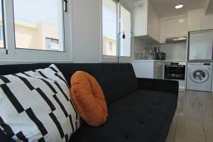 un sofá negro con una almohada naranja en la sala de estar en Phaedrus Living: Seaside Modern Flat Lighthouse 63, en Pafos 34 fotos más