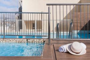 a woman laying on a deck next to a swimming pool at Bayview Hotel by ST Hotels in Il-Gżira