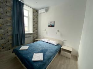 een slaapkamer met een blauw bed en een raam bij Art-Hotel Centralnyi in Kostroma