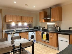 a kitchen with wooden cabinets and a washer and dryer at City Central Apartment in Coventry