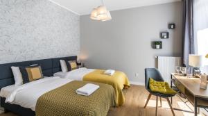 een slaapkamer met 2 bedden, een tafel en een bureau bij Finale Apartments in Krakau
