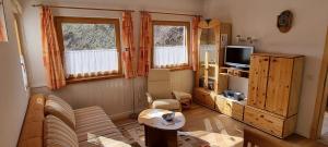 ein Wohnzimmer mit einem Sofa und einem TV in der Unterkunft Appartement MELCHER Sotchà Dadaint 654 in Scuol