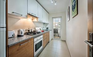 une cuisine avec des armoires blanches et un four à plaques de cuisson dans l'établissement Penthouse Apartment Royal Cabanas Resort, à Cabanas de Tavira