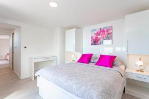 a white bedroom with a large bed with pink pillows at Villa King Apartments in Brela