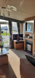 a living room with a couch and a fireplace at Church Farm Haven Holiday Park in Pagham