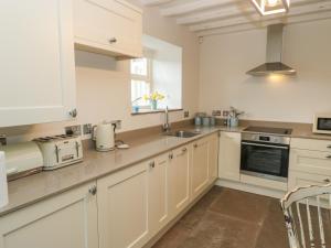 a kitchen with white cabinets and a sink at Clock Cottage in Oldham