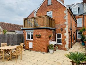 a patio with a wooden deck on a brick building at Shepherds House in Swanage