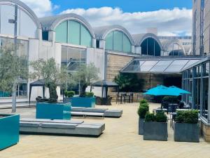 une cour avec des tables et des parasols en face d'un bâtiment dans l'établissement Novotel Sheffield Centre, à Sheffield