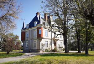 uma grande casa branca com uma árvore em frente em Domaine du Perrier em Sainte-Agathe-la-Bouteresse