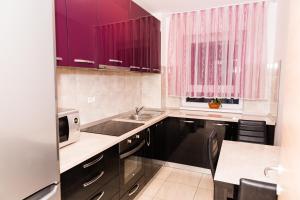una cocina con armarios morados y fregadero en Urban Retreat Luxury HideAway en Oradea