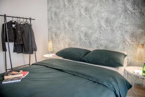 a bedroom with a bed with green sheets and a wall at Apartamenty Rejtana in Leszno
