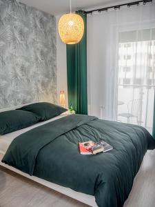 a bedroom with a green bed with a book on it at Apartamenty Rejtana in Leszno