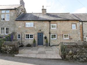 ein altes Steinhaus mit blauer Tür in der Unterkunft Daisy Cottage in Matlock