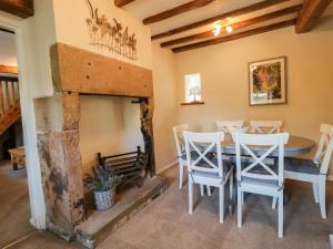 a dining room with a table and a fireplace at Daisy Cottage in Matlock