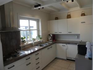 uma cozinha com armários brancos, um lavatório e uma janela em Vakantiewoning De Nachtegaal em Oostende