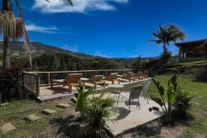 a group of chairs and tables on a deck with a mountain at Soy Local Guatape in Guatapé +37 photos