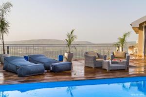 a swimming pool with couches and chairs next to at Nof Lazafon in Kerem Ben Zimra