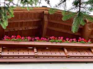 a wooden balcony with pink flowers on it at Das Bürstegg in Lech am Arlberg