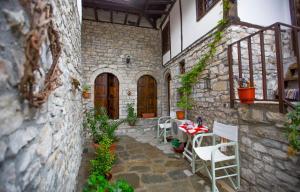 un patio con mesa y sillas en un edificio de piedra en Bujtina Kodiket Guesthouse en Berat