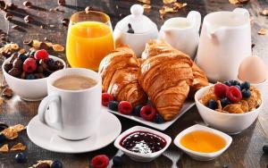 - une table avec petit-déjeuner composé de croissants, de café et de fruits dans l'établissement Villa Francesca Relais, à Gradara