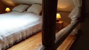 een slaapkamer met een bed met witte lakens en een spiegel bij Gîte Montrias in Cerfontaine