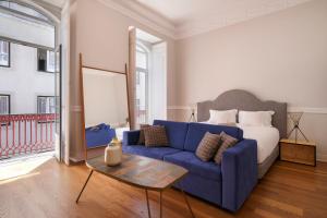 1869 Príncipe Real House في لشبونة: غرفة معيشة مع أريكة زرقاء وسرير